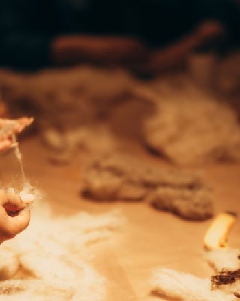 Hands drawing a thread of wool in a felting workshop