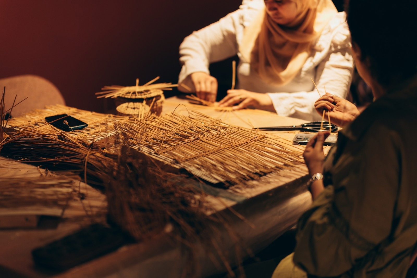 Weaving plant fibres around a workshop table